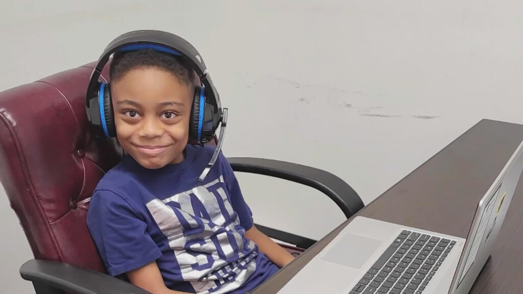 A young boy wearing a headset at the computer