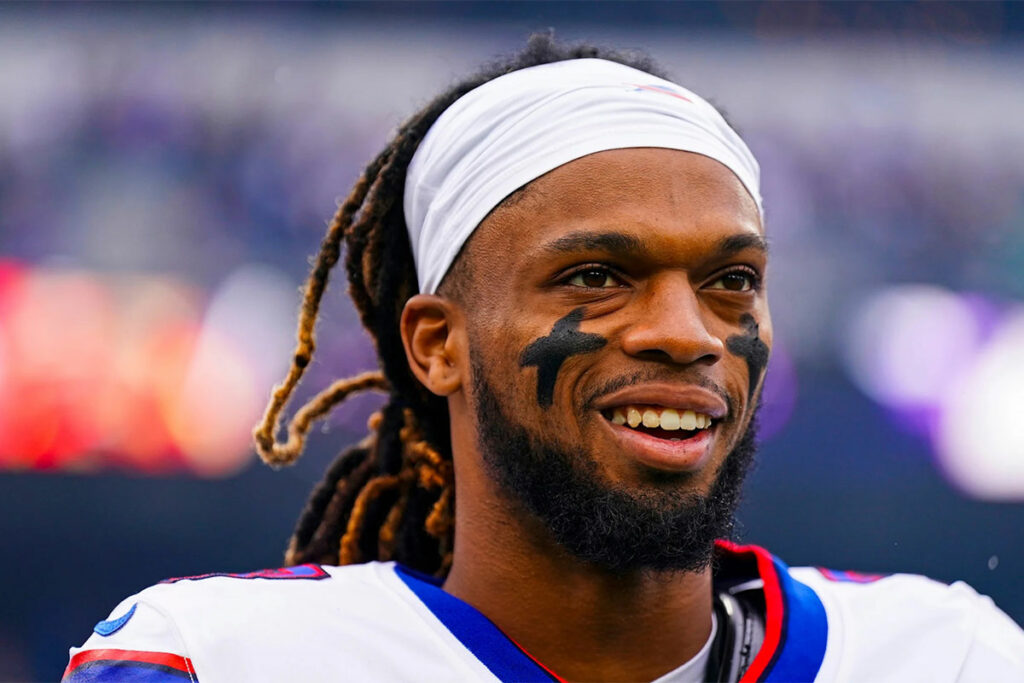 Football player Damar Hamlin smiling with Crosses painted on his cheeks,