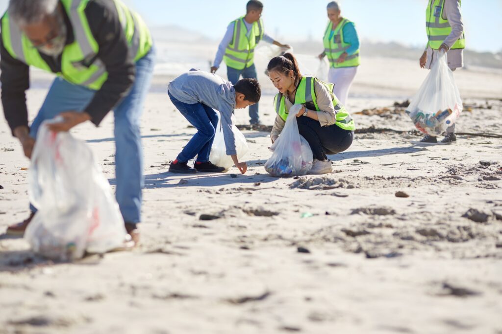 Several people picking up trash on the beach toegther