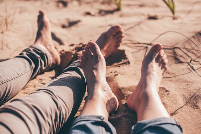 Two pairs of bare feet in the sand