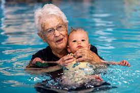 An older woman teaching an infant how to swim