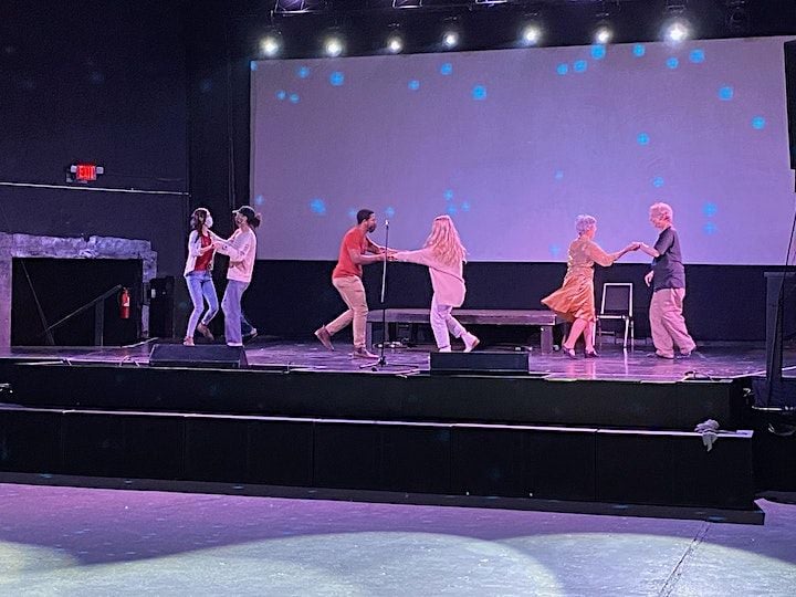 Three sets of couples swing dancing on a stage under lights