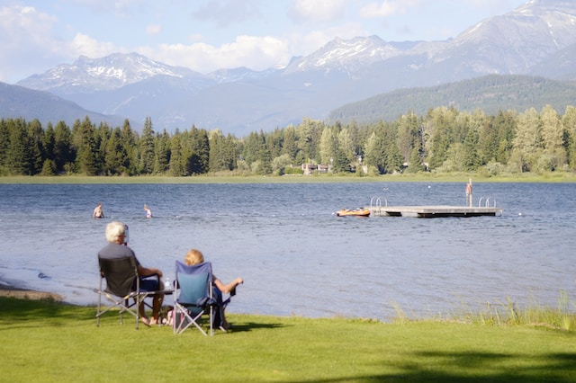 Two elderly people sitting on chairs looking out at a lake