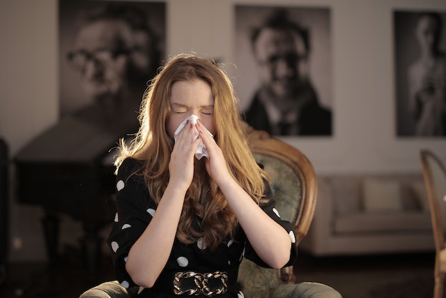 Woman sneezing into a tissue