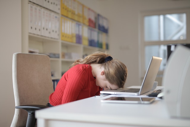 A girl with her head on her computer